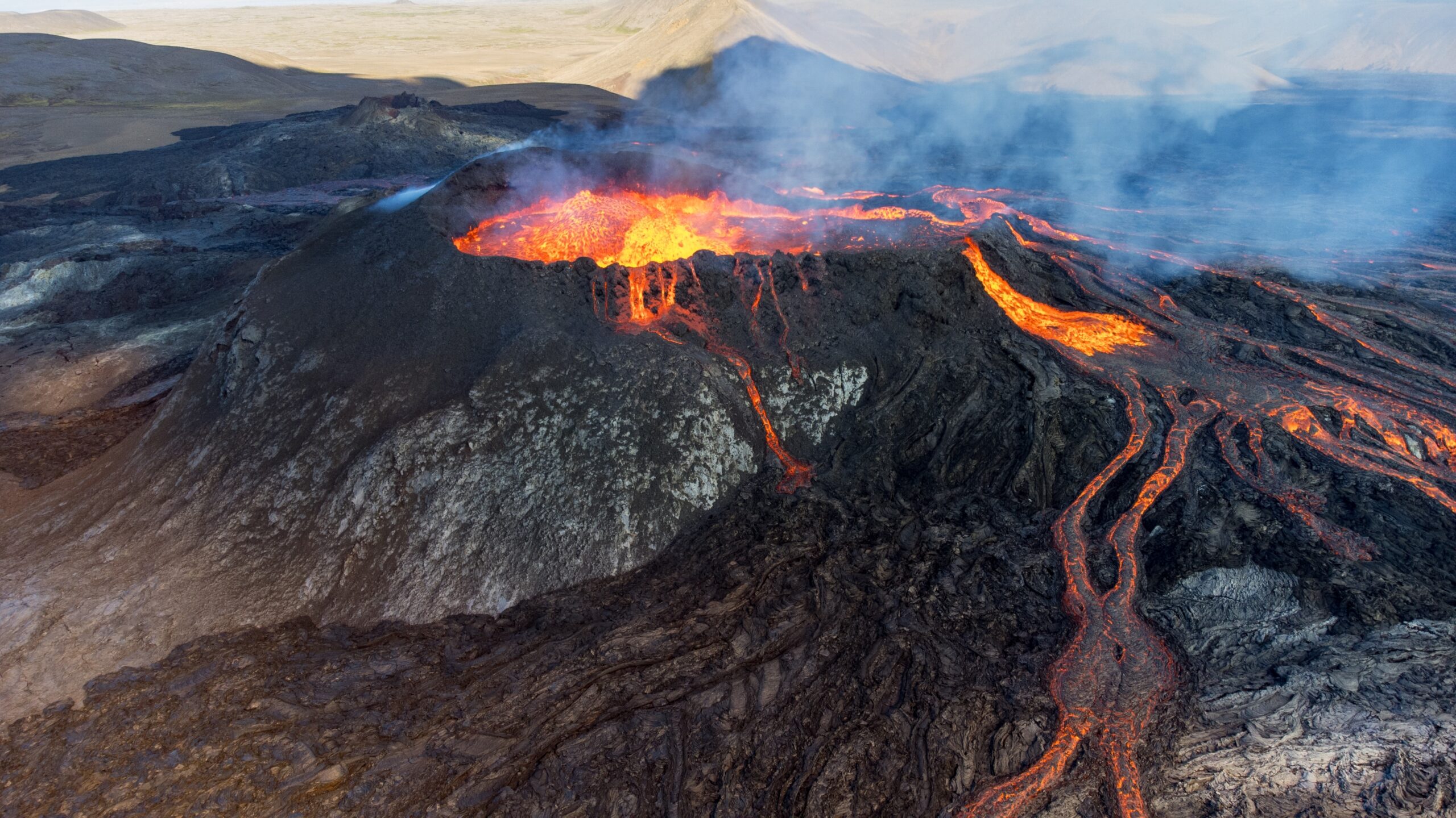 Lava brodelt aus einem steinigen, schwarzen Vulkan.